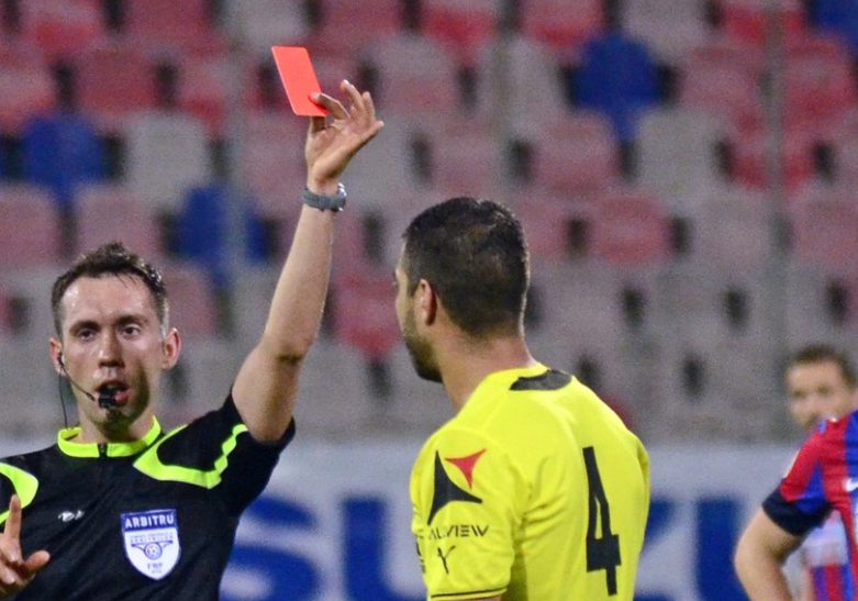 A referee shows a red card to send a player off