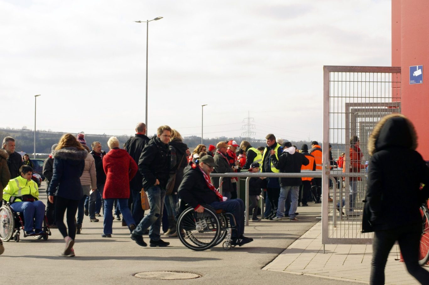 A supporter in a wheelchair pushing themselves through the gate and into a football stadium.